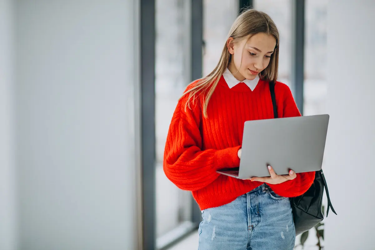 girl-student-with-laptop-standing-by-window-corridor.jpg